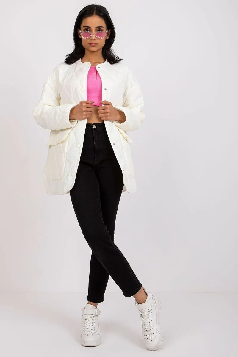 Cream quilted jacket with snap closure over a pink crop top and black jeans, worn by a model.
