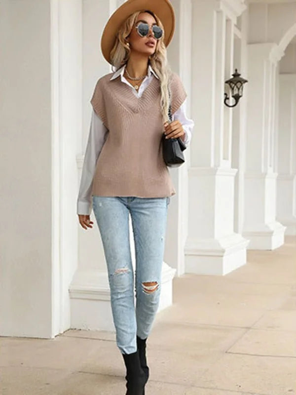 Woman in light blue distressed jeans, white shirt, and tan v-neck sweater vest, wearing a tan hat and black boots.