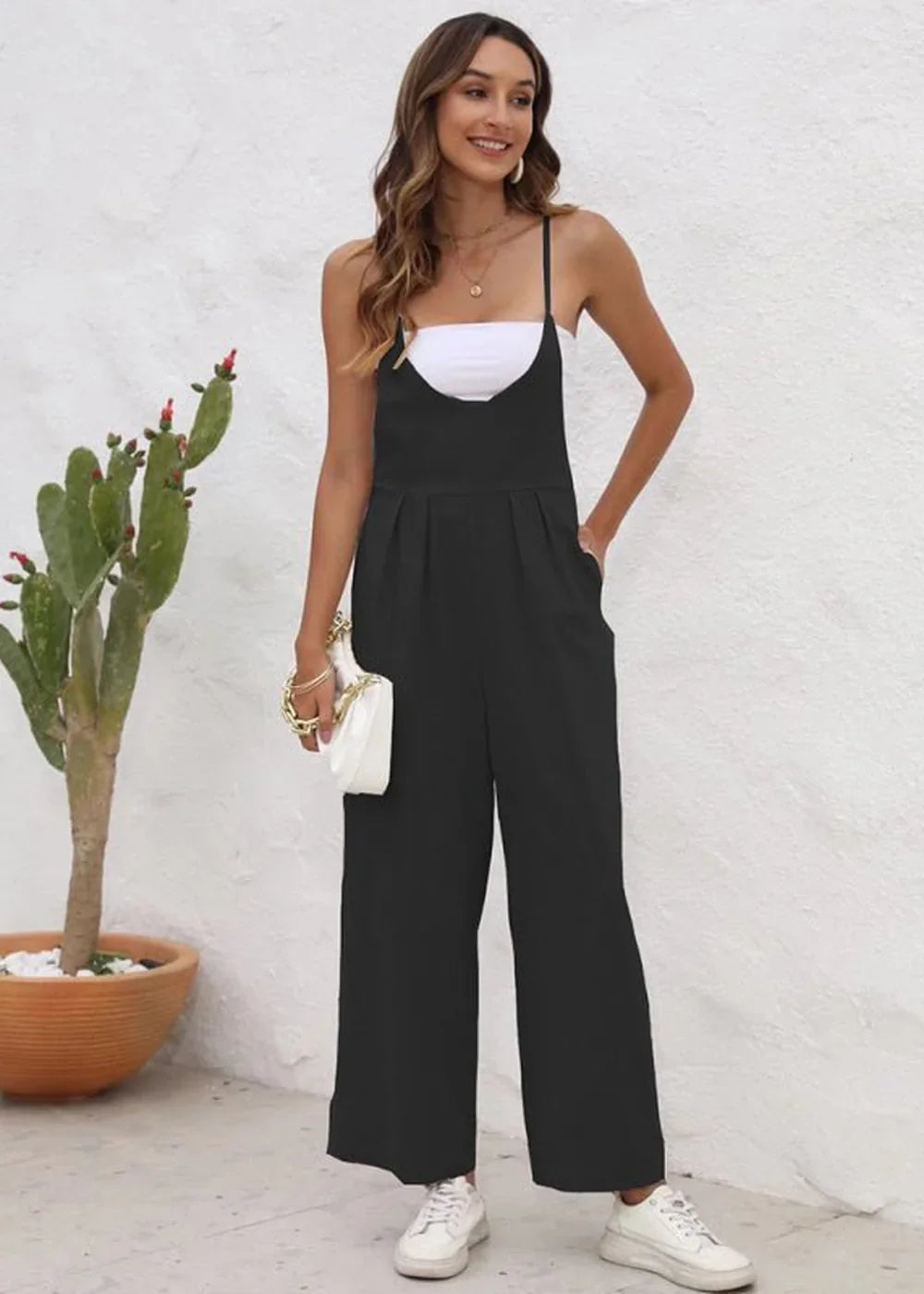 Full-length black jumpsuit with wide legs and a white bandeau top underneath, worn by a model.