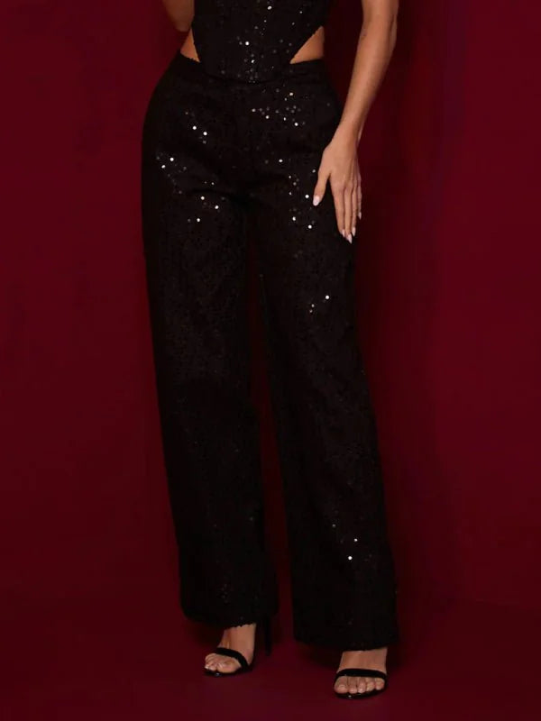 Black sequined wide-leg pants with cut-out waist detail and strappy heels.
