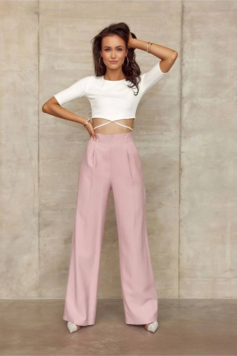 Full-length shot of a woman in a white crop top and high-waisted, wide-leg pink pants made of polyester and viscose blend.