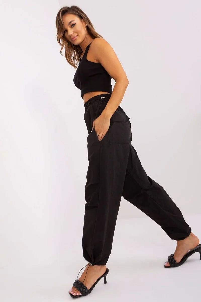 Black cargo pants with drawstring ankles and braided strap heels on model.