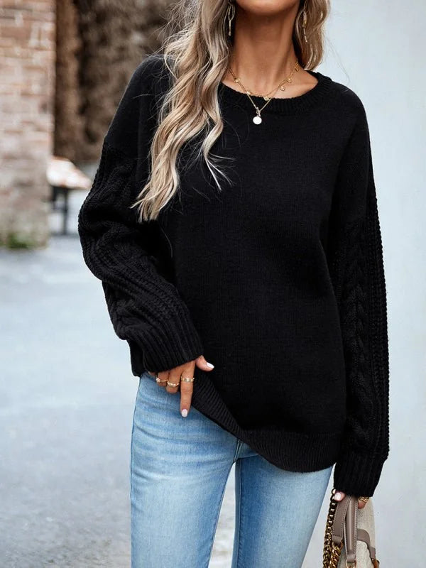Black cable knit sweater with crew neck and light wash jeans on model.
