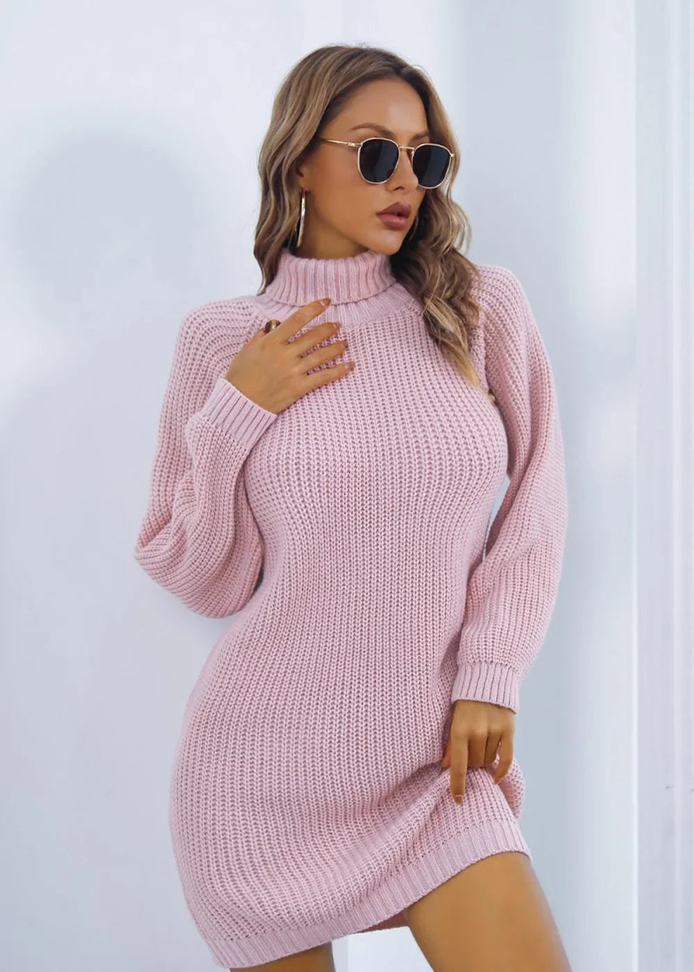 Woman wearing a pink ribbed turtleneck sweater dress with a regular fit.
