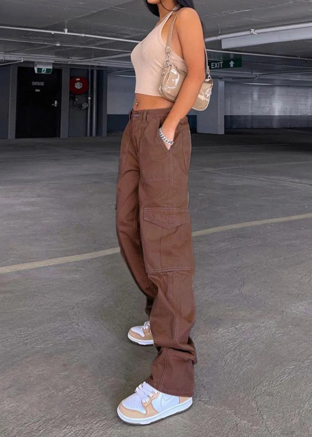 Brown cargo pants with large side pockets and white sneakers on model.