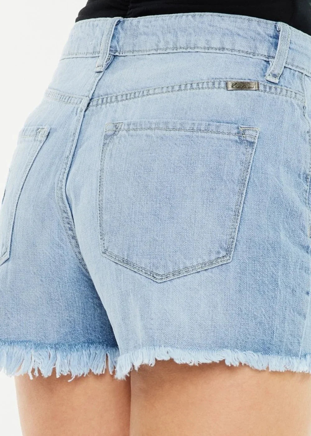 Close-up of light wash denim shorts with frayed hem and back pocket detail.
