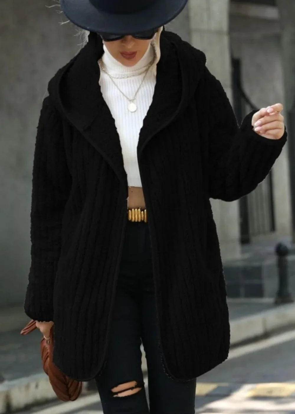Black textured hooded cardigan with a white turtleneck and ripped black jeans on a model.