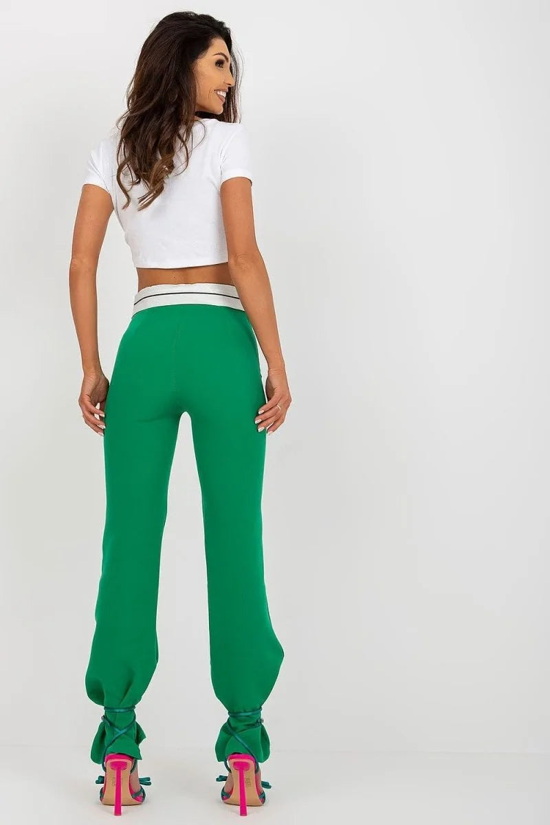 Bright green pants with a white and black waistband and ties at the ankles, on a model.