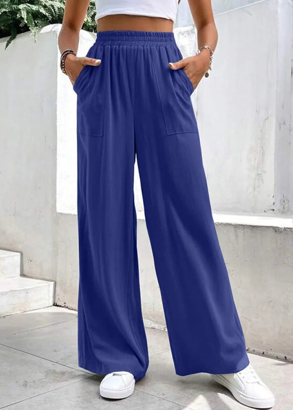 Navy blue wide-leg pants with elastic waistband and pockets, worn by a model with white sneakers.
