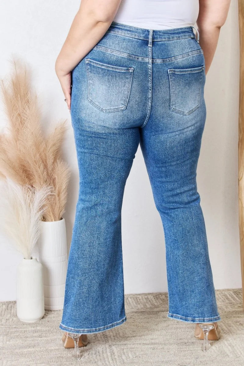 Back view of women's distressed blue denim flare jeans with a regular fit.