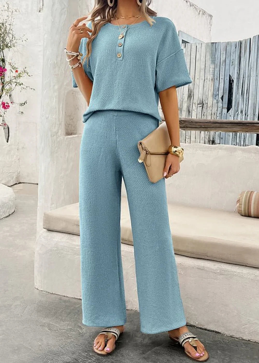 Light blue waffle-knit pant suit with short sleeves and button detail, worn by a model with accessories.