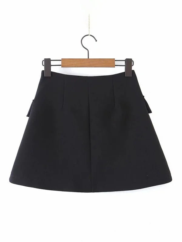 Black A-line mini skirt with subtle pleats and decorative side bows, hanging on a wooden hanger.