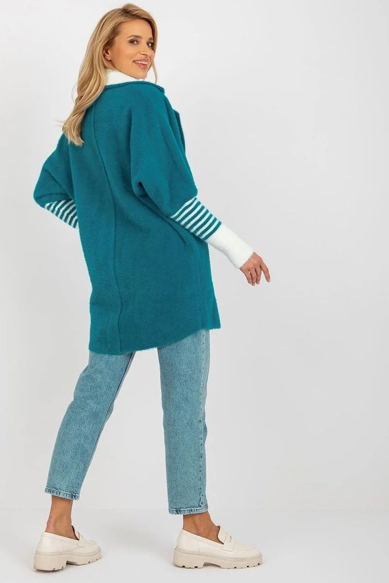 Teal angora blend jacket with white striped cuffs and white turtleneck, worn with light wash jeans.