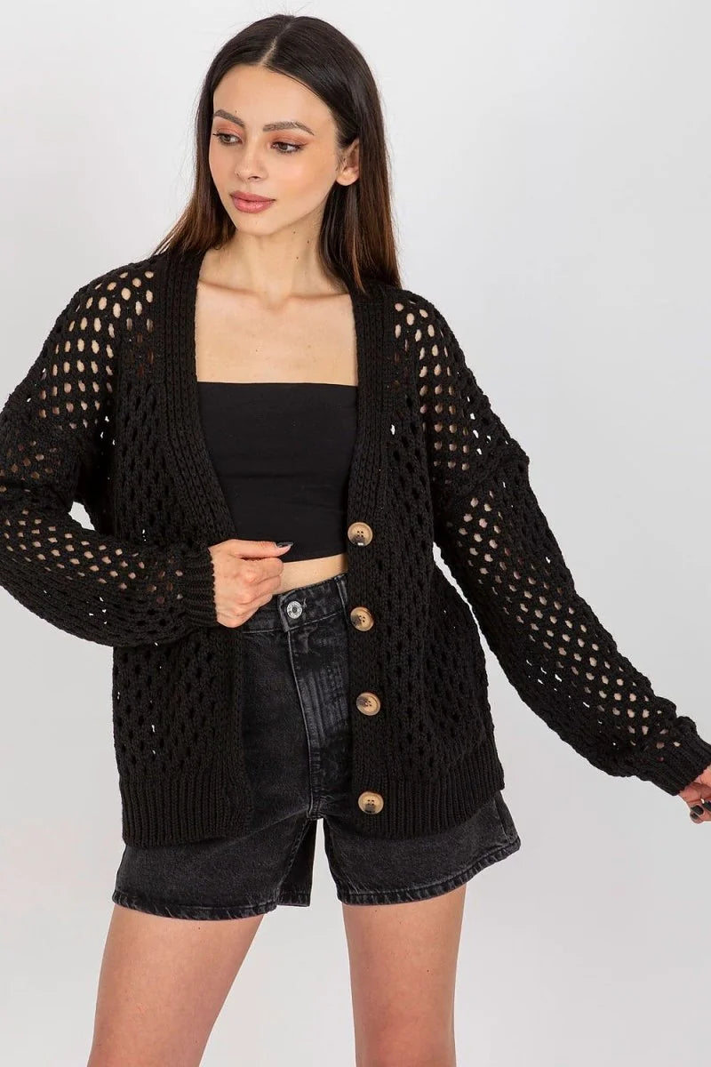 Black crochet knit cardigan with wooden buttons over a black tube top and denim shorts.