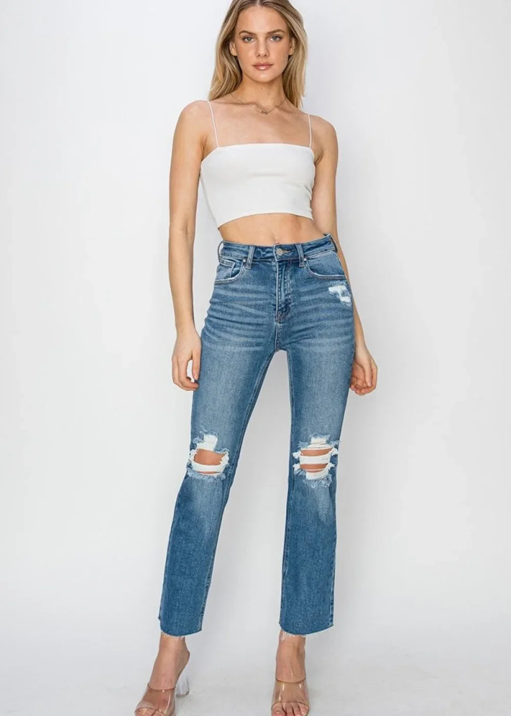 Medium wash distressed denim jeans with ripped knees and frayed hem.