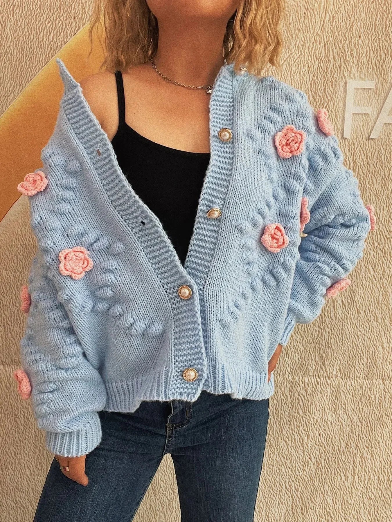 Light blue knit cardigan with pink floral appliqués and pearl buttons.