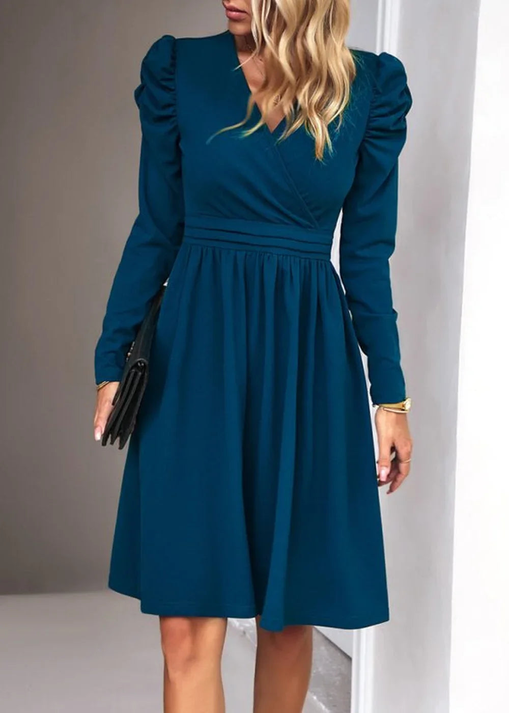 Teal long-sleeve wrap dress with puff sleeves and a cinched waist, held by a model.