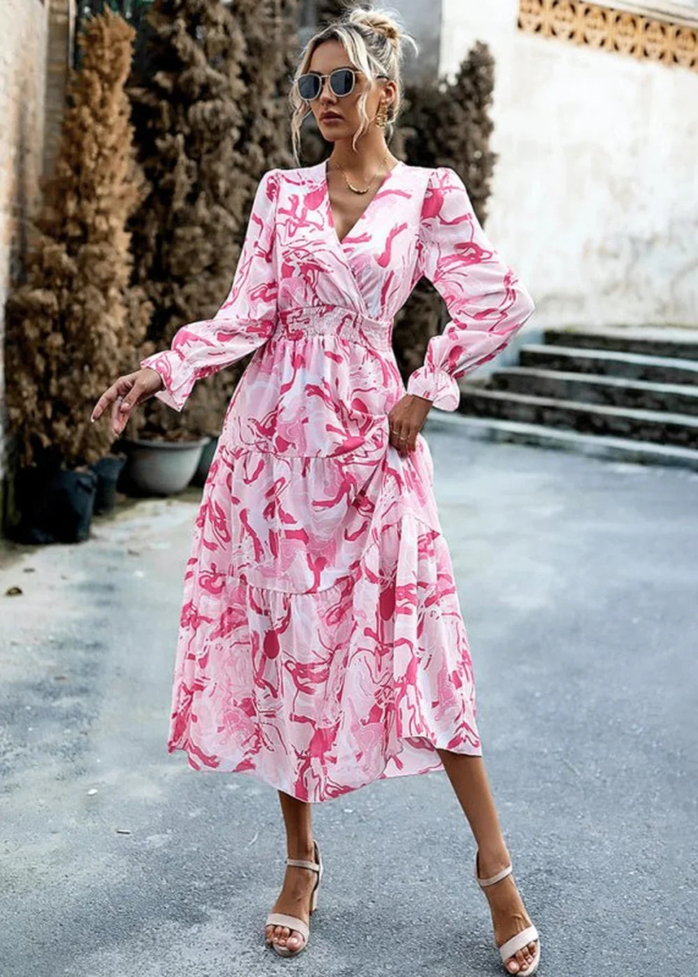 Pink and white abstract print dress with a V-neck, long sleeves, and tiered skirt.