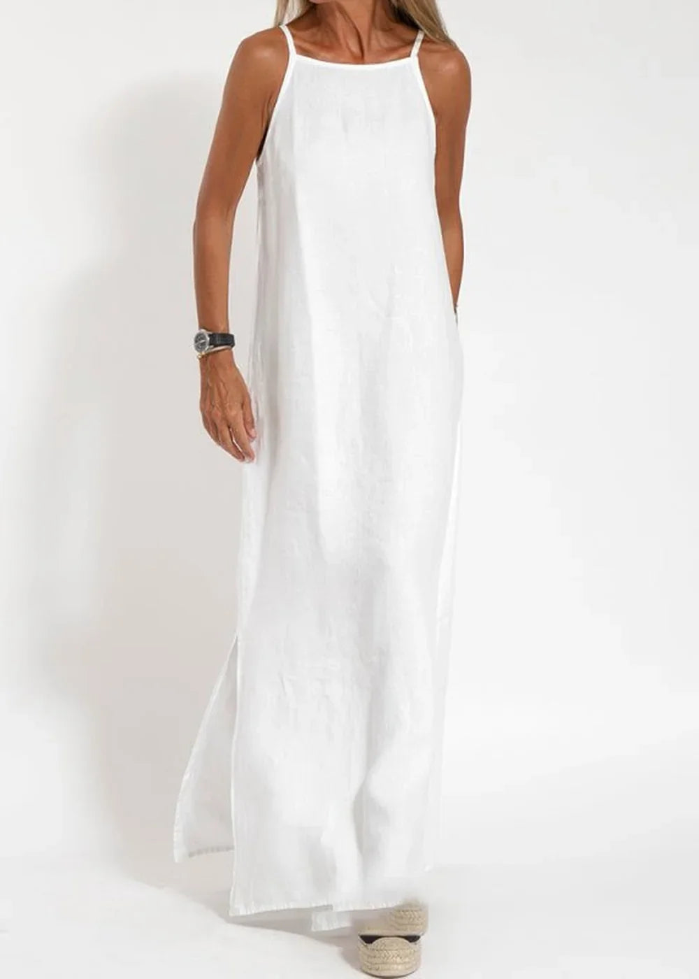Full-length white cotton-blend maxi dress with spaghetti straps and side slits, worn by a model.