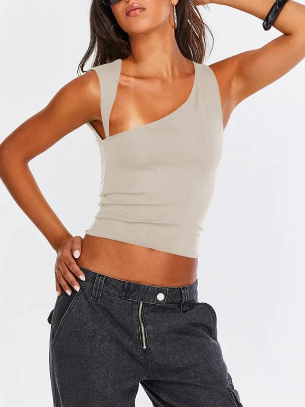 Tan one-shoulder ribbed crop top with a subtle sheen, worn with dark wash denim cargo pants.