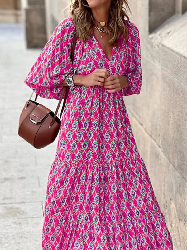 Flowy fuchsia maxi dress with a geometric diamond pattern in green and purple, featuring a V-neck and tiered skirt.
