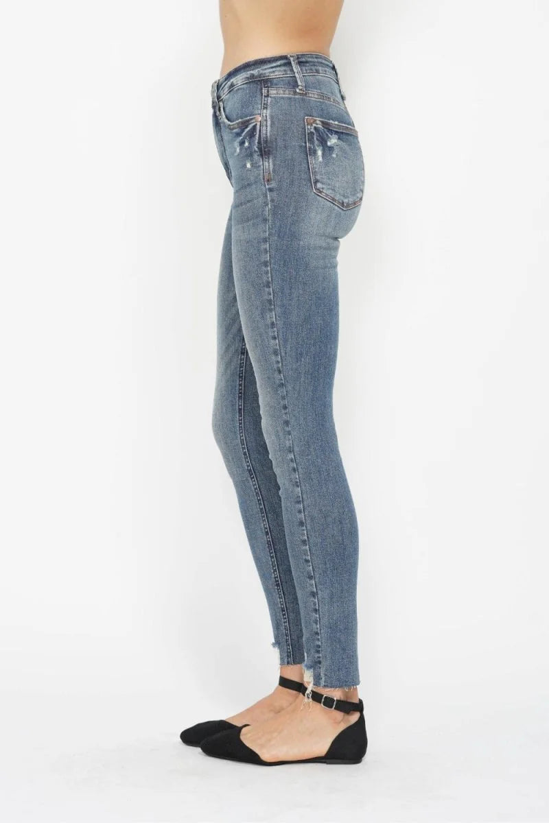 Side view of a woman wearing distressed light wash skinny jeans with frayed hems and black ankle strap flats.