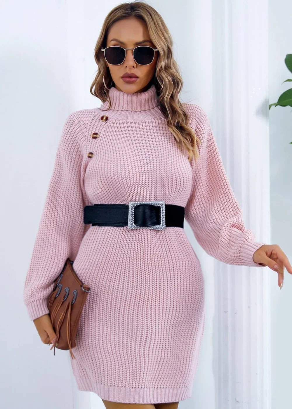 Pink knit turtleneck sweater dress with black jeweled belt and fringe detail clutch.