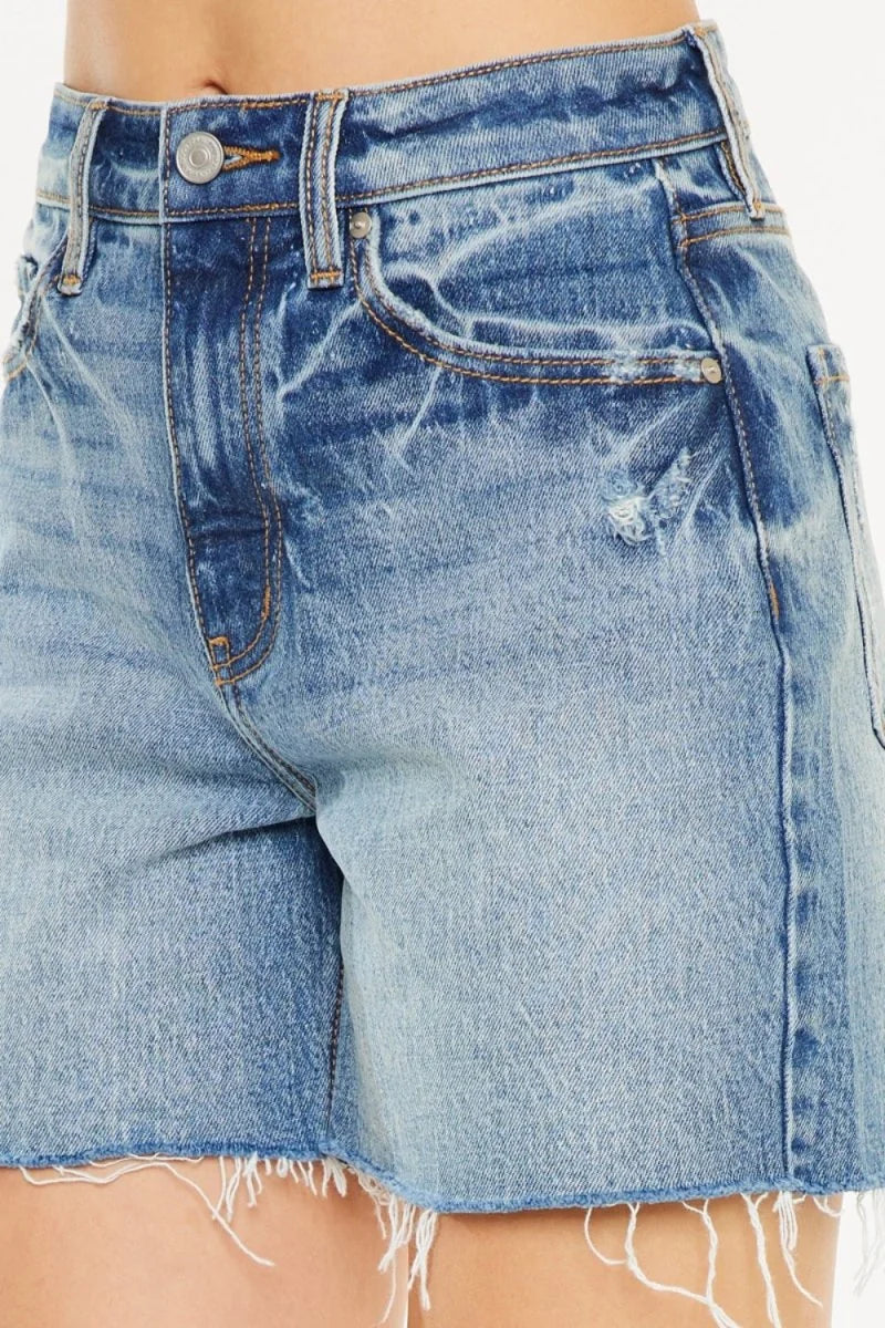 Close-up of light wash distressed denim shorts with frayed hem and visible pocket details.