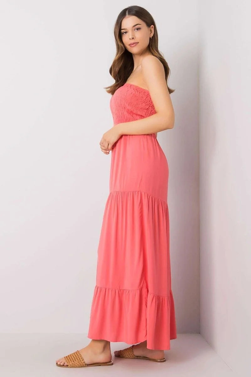 Coral strapless maxi dress with smocked bodice and tiered skirt, worn with woven slides.