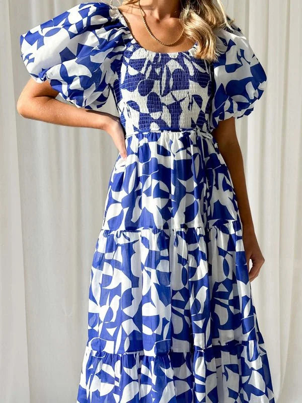 Blue and white abstract print tiered maxi dress with puff sleeves and smocked bodice.