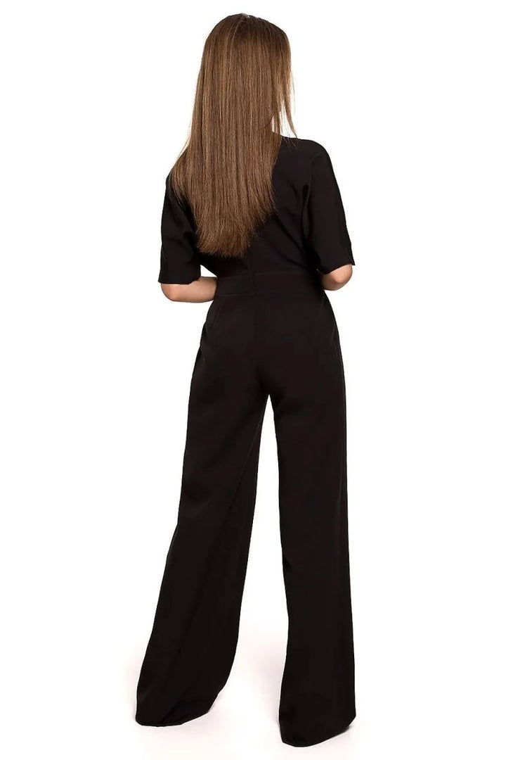 Back view of a woman wearing a black relaxed fit jumpsuit with wide legs.