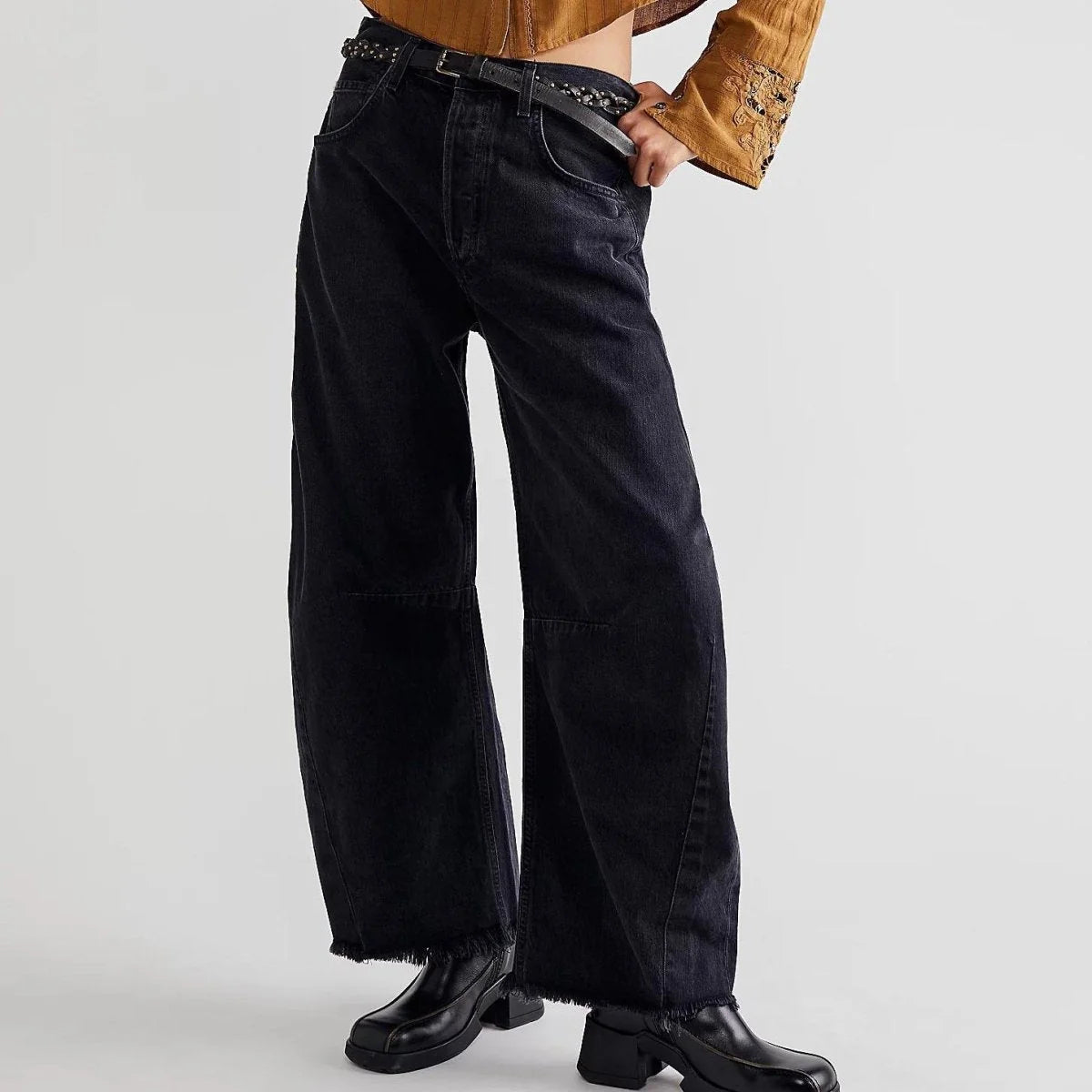 Black high-waisted wide-leg jeans with frayed hems and a chain belt on model.