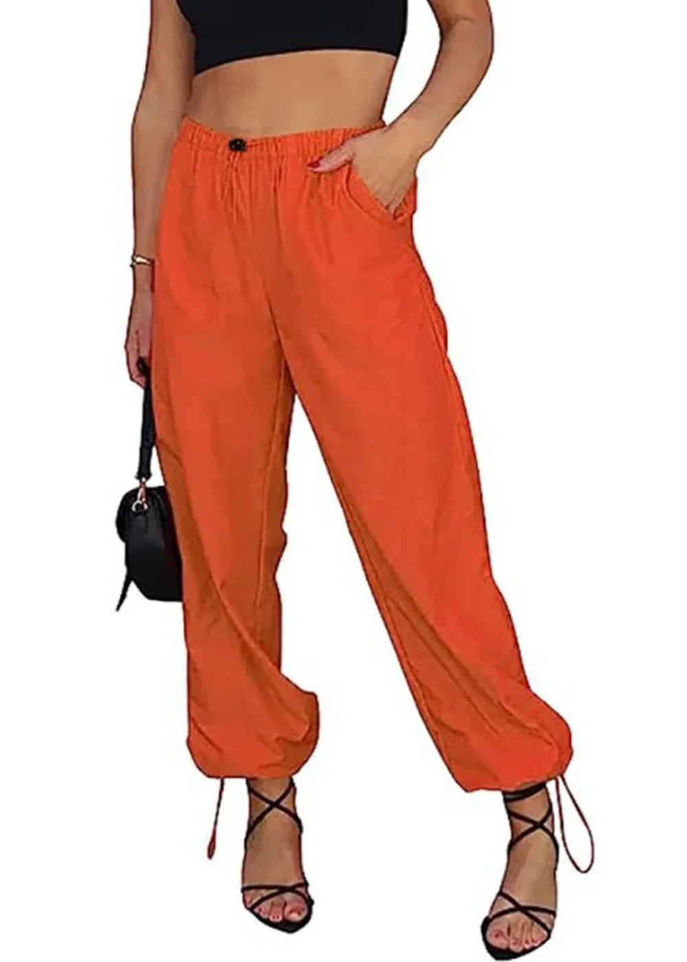 Orange drawstring cargo pants with a cinched ankle and black lace-up heels on a model.