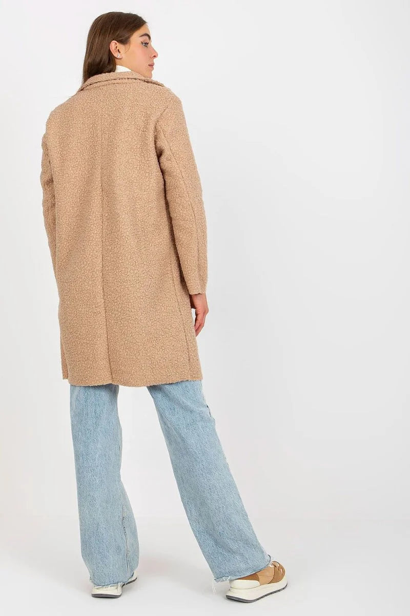 Back view of woman wearing a fuzzy tan coat and light blue wide-leg jeans.