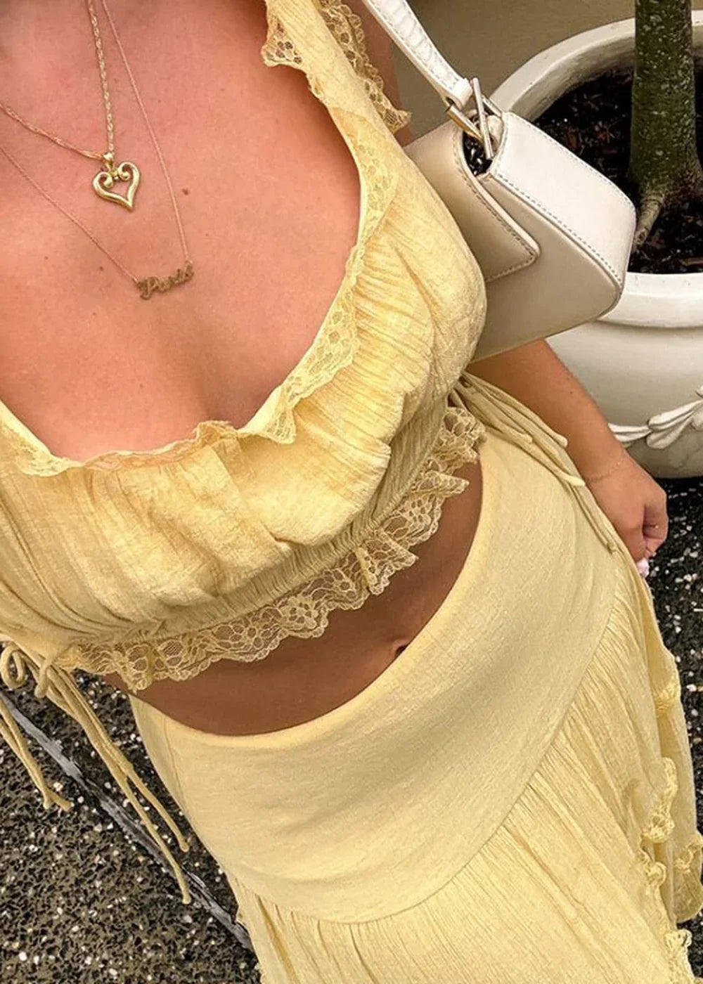 Pale yellow ruffled crop top and skirt with lace trim, close-up showing texture and detail.