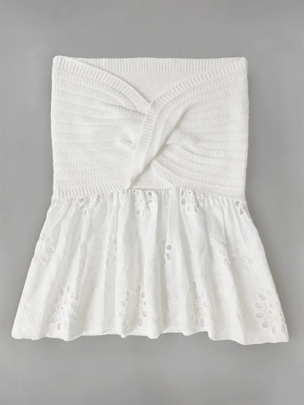 White strapless knit top with a twisted bodice and eyelet peplum hem.