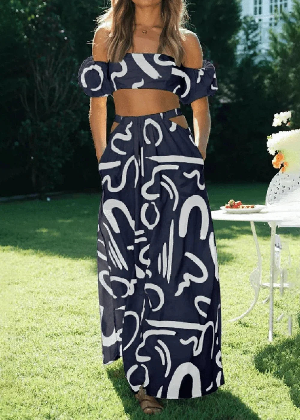 Navy blue and white abstract print off-the-shoulder crop top and high-waisted maxi skirt set with cutouts.