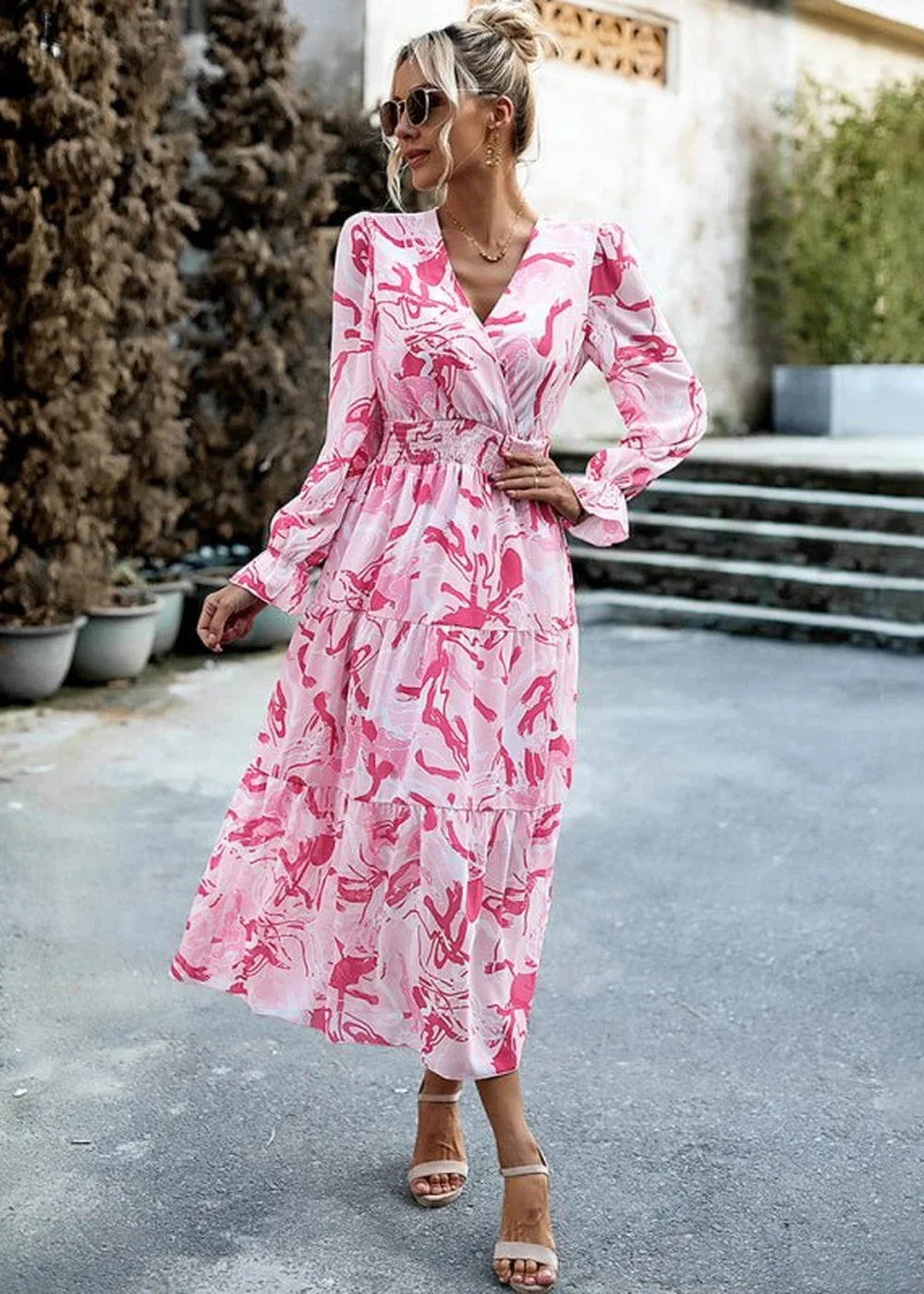 Pink and white abstract print maxi dress with V-neck and tiered skirt, on model.