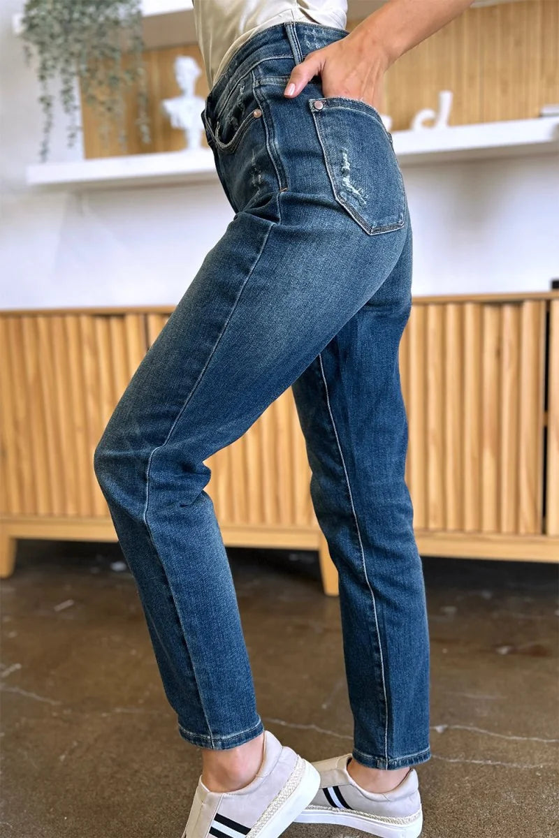 Distressed dark wash denim jeans with a regular fit, shown on a model from the waist down.