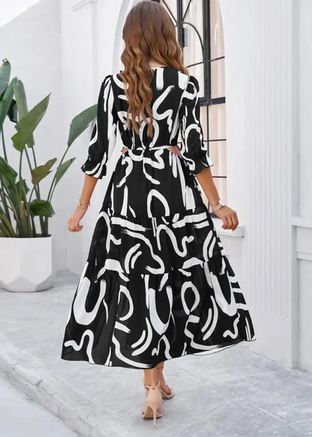 Black and white abstract print midi dress with tiered skirt and cutouts, on model.