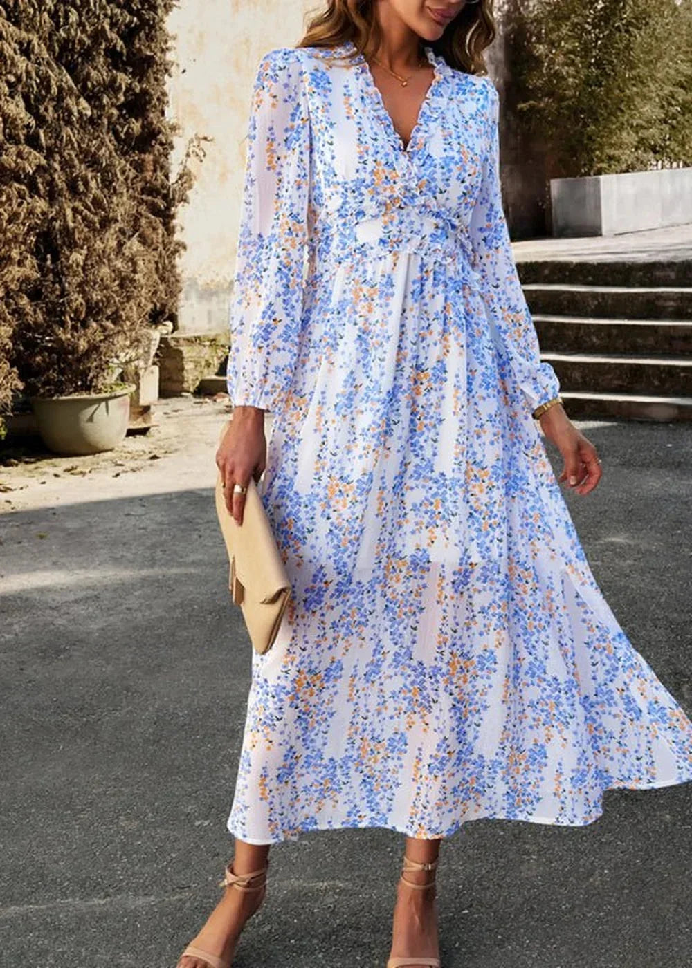 Flowy white maxi dress with blue and orange floral print, V-neck, and long sleeves.
