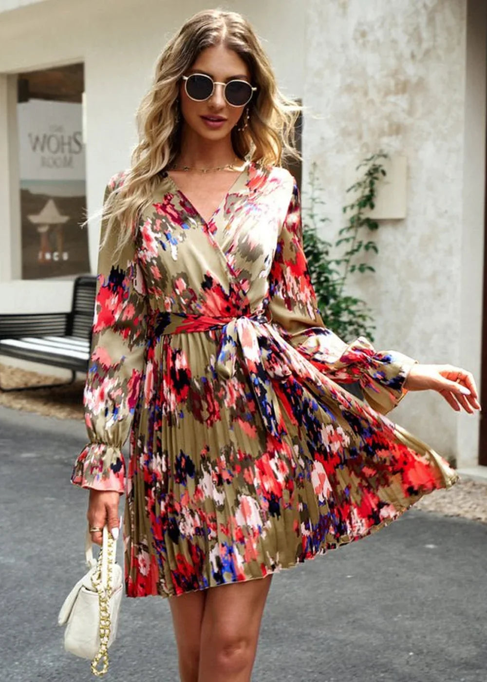 Green wrap dress with a colorful floral print, pleated skirt, and bell sleeves, held by a model.