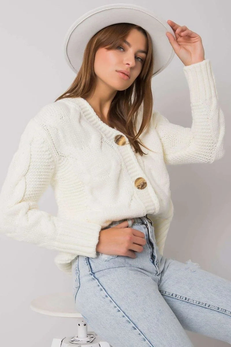 Cream cable knit cardigan with large wooden buttons and a relaxed fit, worn by a model.