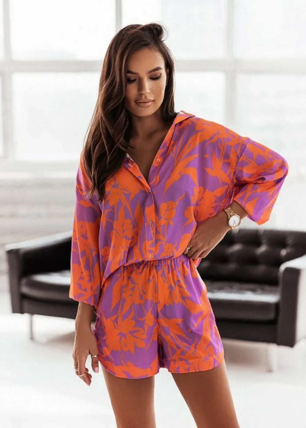 Orange and purple floral print short suit with a collared shirt and elastic waist shorts.