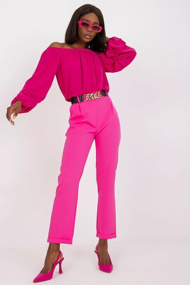 Hot pink high-waisted trousers with a chain belt on a model.