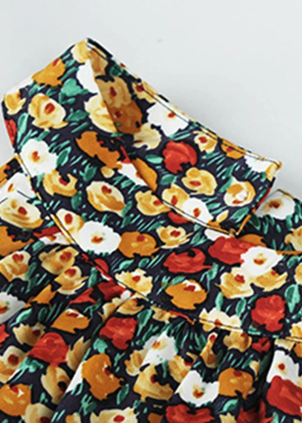 Dark blue day dress with a vibrant floral print of yellow, white, and red flowers with green leaves.