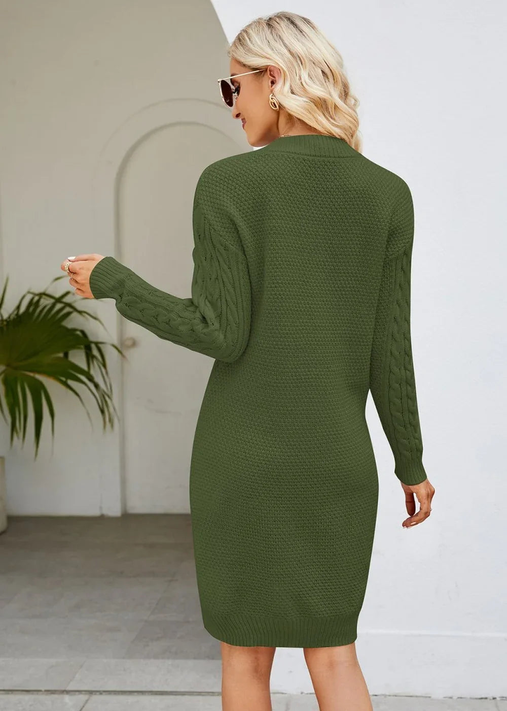 Olive green cable-knit sweater dress with long sleeves, shown from the back on a model.