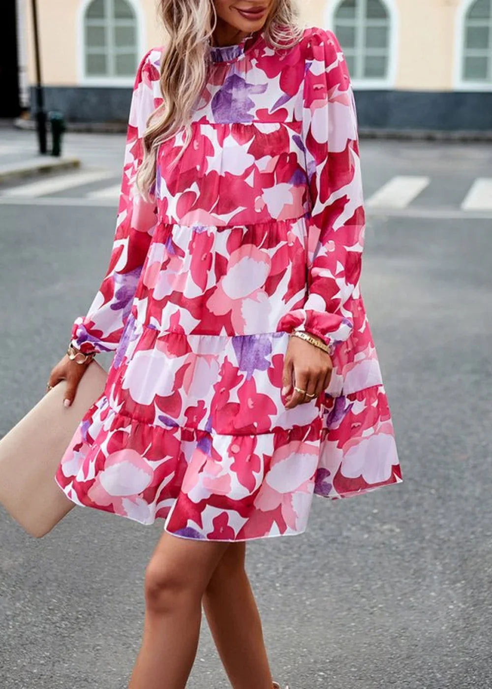 A woman in a tiered floral print dress with long sleeves and a high neckline.