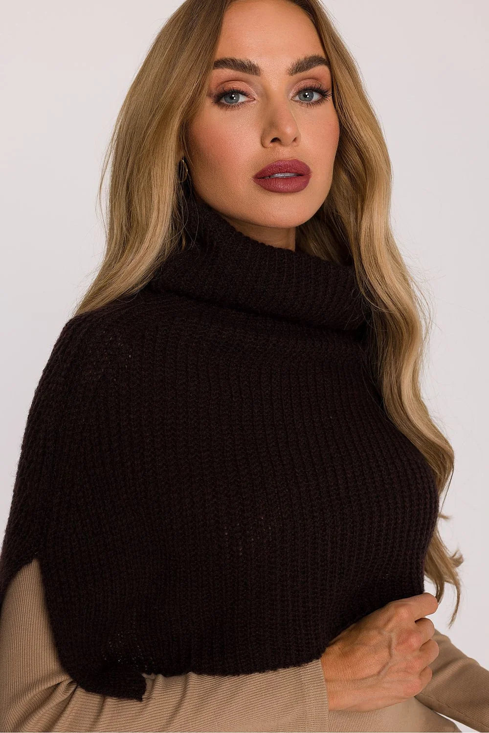 Close-up of a woman's face and shoulders wearing a dark brown chunky knit turtleneck cowl neck sweater.