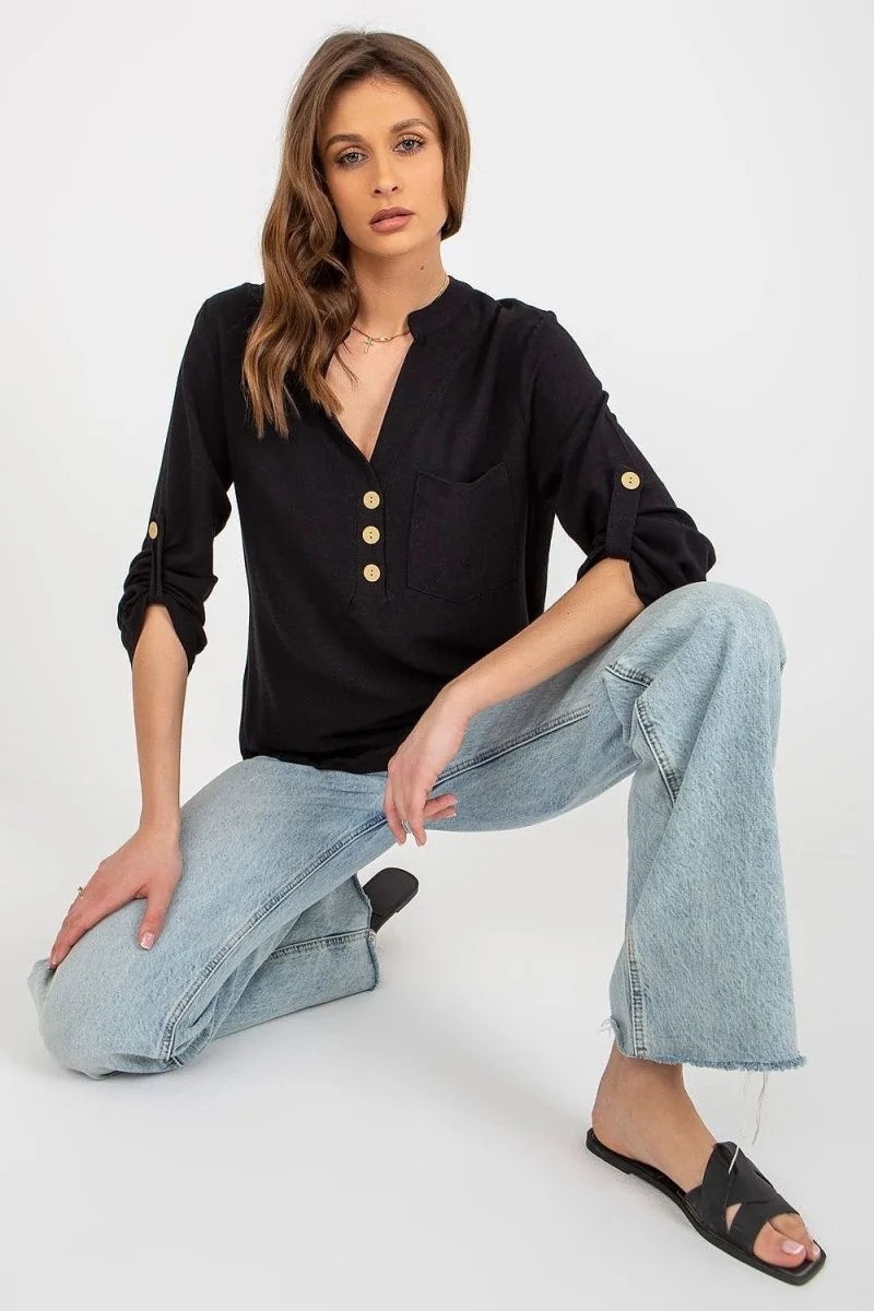 Black linen-blend V-neck shirt with roll-tab sleeves and gold buttons, paired with light wash wide-leg jeans.
